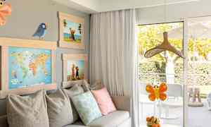 Huone, jossa on sohva, tyynyjä, tauluja sekä pöytä, jossa on hedelmäkulho parvekkeen oven edessä. (Tekoälyn luoma teksti)