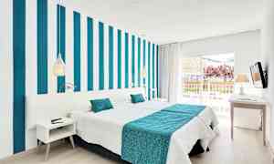 Moderni hotellihuone, jossa raidallinen seinä, valkoiset ja turkoosit vuodevaatteet sekä parveke näkymineen. (Tekoälyn luoma teksti)