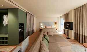 Moderni hotellihuone, jossa on sänky, sohva ja televisio suurien ikkunoiden edessä. (Tekoälyn luoma teksti)