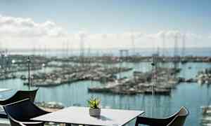 Näkymä venesatamaan, etualalla pöytä ja tuoleja. (Tekoälyn luoma teksti)