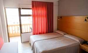 Hotellihuone, jossa kaksi erillistä vuodetta, punainen verho ja parveke. (Tekoälyn luoma teksti)