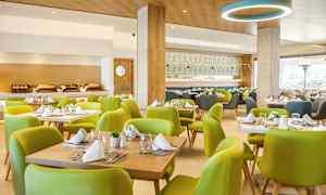 Ravintolan sisätila vihreillä tuoleilla ja katetuilla pöydillä. (Tekoälyn luoma teksti)