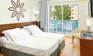 Kuva valoisasta hotellihuoneesta, jossa on kaksi yhden hengen vuodetta, koristeellinen seinäkoriste, parveke ulkokalusteineen ja vaaleat verhot. (Tekoälyn luoma teksti)