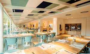 Ravintolan sisätila, jossa katettuja pöytiä ja vaalea sisustus. (Tekoälyn luoma teksti)