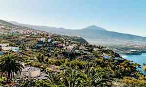 Näköala kumpuilevaan maisemaan taloineen ja kasvillisuuksineen sekä taustalla oleva vuorenhuippu. (Tekoälyn luoma teksti)