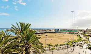 Ranta palmuilla, ihmisillä ja rakennuksilla taustalla. (Tekoälyn luoma teksti)