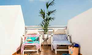 Kaksi aurinkotuolia pyyhkeiden ja tyynyjen kanssa terassilla, jossa välissä kukkaruukku. (Tekoälyn luoma teksti)