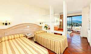 Hotellihuone, jossa kaksi yhden hengen vuodetta, oleskelutila ja parveke. (Tekoälyn luoma teksti)