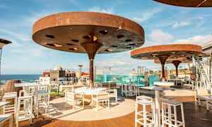 Ulkona sijaitseva ruokailualue, jossa on modernit katokset ja näkymä merelle. (Tekoälyn luoma teksti)