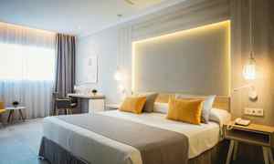 Moderni hotellihuone, jossa on parivuode, kirjoituspöytä ja istuinryhmä. (Tekoälyn luoma teksti)