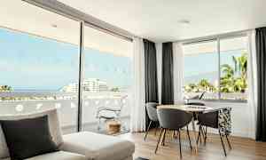 Valoisa huone, jossa on isot ikkunat ja näkymä merelle ja vehreään maisemaan. (Tekoälyn luoma teksti)