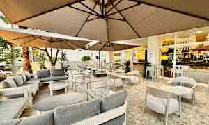 Ulkoravintola-alue, jossa sohvia ja pöytiä varjojen alla. (Tekoälyn luoma teksti)