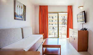 Loma-asunnon olohuone, jossa sohva, sohvapöytä, lipasto ja TV sekä parveke ulkokalusteilla. (Tekoälyn luoma teksti)