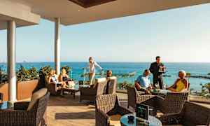 Henkilöitä, jotka istuvat terassilla ja katselevat merinäkymää. (Tekoälyn luoma teksti)