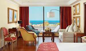 Huone, jossa punaiset verhot, huonekalut ja näkymä merelle. (Tekoälyn luoma teksti)