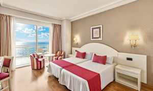 Hotellihuone, jossa kaksi vuodetta, punaiset yksityiskohdat ja merinäköala parvekkeelta. (Tekoälyn luoma teksti)