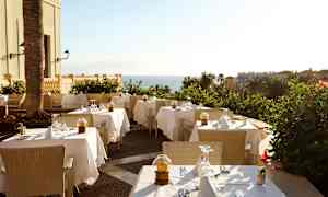 Kuva ulkoilmaravintolasta, jossa katetut pöydät ja merinäköala. (Tekoälyn luoma teksti)