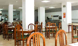 Kahvila tai ravintola, jossa on puutuolit ja -pöydät sekä valkoiset pylväät suuressa avoimessa tilassa. (Tekoälyn luoma teksti)