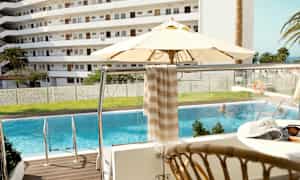 Kuva uima-altaasta, aurinkovarjosta ja parvekkeesta näkymällä asuinalueelle. (Tekoälyn luoma teksti)