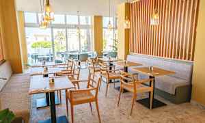 Moderni kahvila, jossa pöytiä ja tuoleja sekä vaaleita sävyjä. (Tekoälyn luoma teksti)