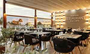 Valoisasti valaistu ravintolaympäristö, jossa tyylikkäästi katetut pöydät ja tuolit. (Tekoälyn luoma teksti)