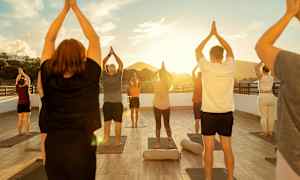 Ryhmä ihmisiä tekee joogaliikkeitä ulkoilmalavalla auringonlaskun aikaan. (Tekoälyn luoma teksti)