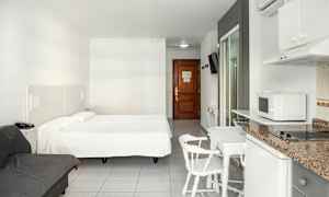 Hotellihuone, jossa parivuode, sohva, ruokapöytä tuoleineen ja minikeittiö. (Tekoälyn luoma teksti)