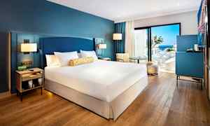 Hotellihuone, jossa on parisänky, istuinkalusteita ja näkymä merelle. (Tekoälyn luoma teksti)