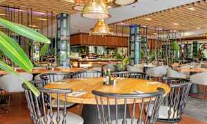 Ravintolan sisätila, jossa puupöytiä, tuoleja ja vihreitä koristeita. (Tekoälyn luoma teksti)