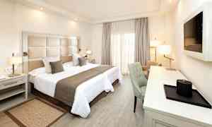 Hotellihuone, jossa on parivuode, kirjoituspöytä ja tuoli. (Tekoälyn luoma teksti)