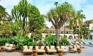 Terassi, jossa on mukavat istuimet trooppisten kasvien keskellä ja näkymät uima-altaalle. (Tekoälyn luoma teksti)