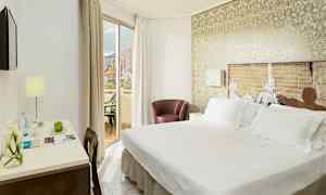 Hotellihuone, jossa on parivuode, työpöytä lampulla ja parveke näkymällä. (Tekoälyn luoma teksti)