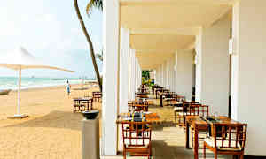 Ulkoterassi, jossa on ruokapöytiä ja tuoleja hiekkarannan vieressä. (Tekoälyn luoma teksti)