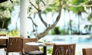 Katettu pöytä ja tuolit ulkona uima-altaan vieressä, ympärillä puita ja kasvillisuutta. (Tekoälyn luoma teksti)