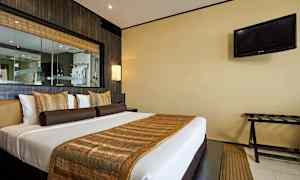 Hotellihuone, jossa on parivuode, koristeltu ruskeilla ja kultaisilla yksityiskohdilla. TV on seinällä oikealla. (Tekoälyn luoma teksti)