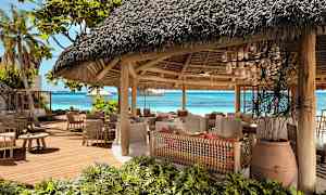 Avoin ravintola, jossa on olkikatto lähellä rantaa. (Tekoälyn luoma teksti)