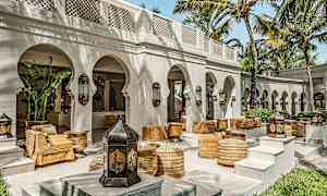 Ulkoterassi, jossa on kaaria, palmuja ja arabialaisesta suunnittelusta inspiroituja istumapaikkoja. (Tekoälyn luoma teksti)