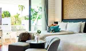 Hotellihuone, jossa on parivuode, oleskelutila ja parveke maisemalla. (Tekoälyn luoma teksti)