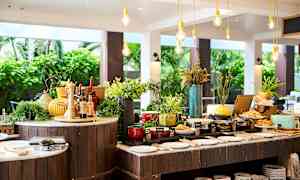 Buffetpöytä eri ruokavaihtoehtojen ja koristeiden kanssa, sijoitettu avoimeen ja valoisaa ympäristöön. (Tekoälyn luoma teksti)