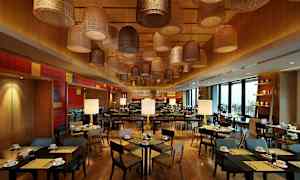 Ravintola, jossa on puusisustus, modernit pöydät ja tuolit sekä koristeelliset kattovalaisimet erilaisissa tyyleissä. (Tekoälyn luoma teksti)