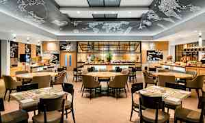 Moderni ravintolasisustus, jossa on pöytiä ja tuoleja sekä tarjoilubuffet taustalla. (Tekoälyn luoma teksti)