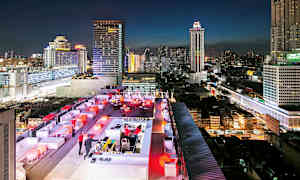 Kattobaari iltavalaistuksessa, taustalla korkeita rakennuksia kaupunkimaisemassa. (Tekoälyn luoma teksti)