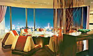 Tyylikäs ruokasali, josta on panoraamanäkymä valaistuun kaupunkiin illalla. (Tekoälyn luoma teksti)