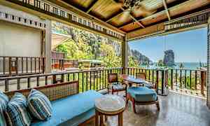 Terassi kattavalla istuinalueella, josta on näkymä vehreään trooppiseen maisemaan ja taustalla näkyvään mereen. (Tekoälyn luoma teksti)