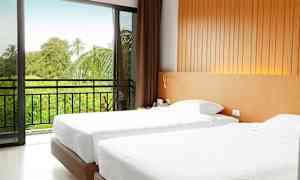 Hotellihuone, jossa on kaksi yhden hengen vuodetta. Liukuovi johtaa parvekkeelle, josta avautuu näkymä vehreään maisemaan. (Tekoälyn luoma teksti)