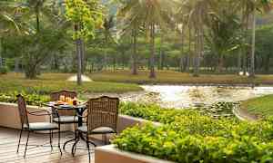 Ulkoterassi, jossa pöytä ja tuolit, ympärillä vehreää ja näkymä lammelle. (Tekoälyn luoma teksti)