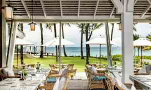 Ravintola, jossa istumapaikkoja ja näköala vihreälle nurmikolle, aurinkovarjoille ja merelle. (Tekoälyn luoma teksti)