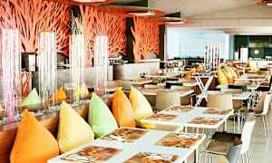 Moderni ravintola, jossa on valkoiset pöydät, värikkäät tyynyt ja koristeita. (Tekoälyn luoma teksti)