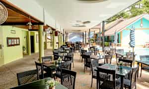 Ulkona oleva ravintola, jossa on pöytiä ja tuoleja uima-altaan vieressä. (Tekoälyn luoma teksti)