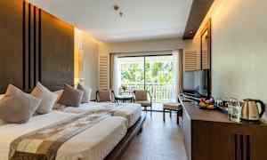 Hotellihuone, jossa on kaksi sänkyä, istuinryhmä, parveke ja televisio. (Tekoälyn luoma teksti)